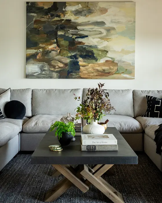 Grace Blu Travertine living room with neutral sectional, abstract art, and dark wood coffee table styled with books and florals.