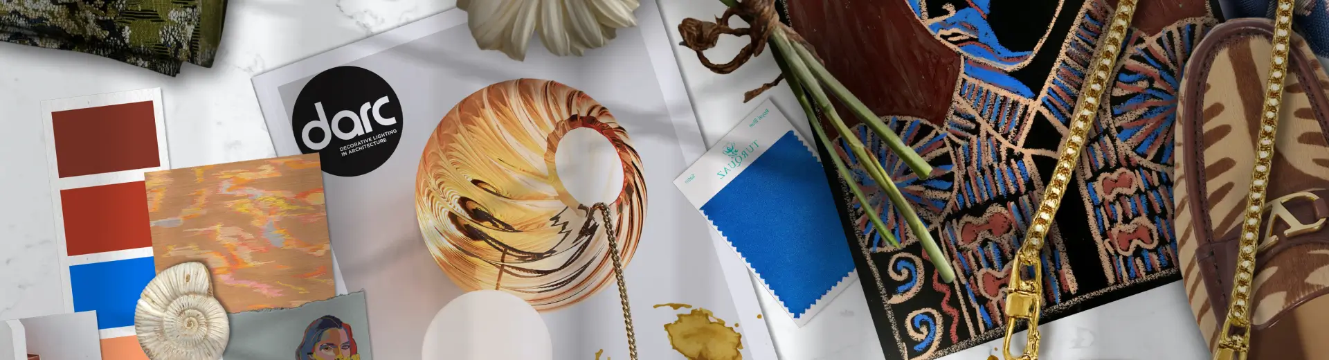 Flat lay with daisies, espresso, bold blue fabric swatch, sunglasses, and artistic design inspiration pieces.