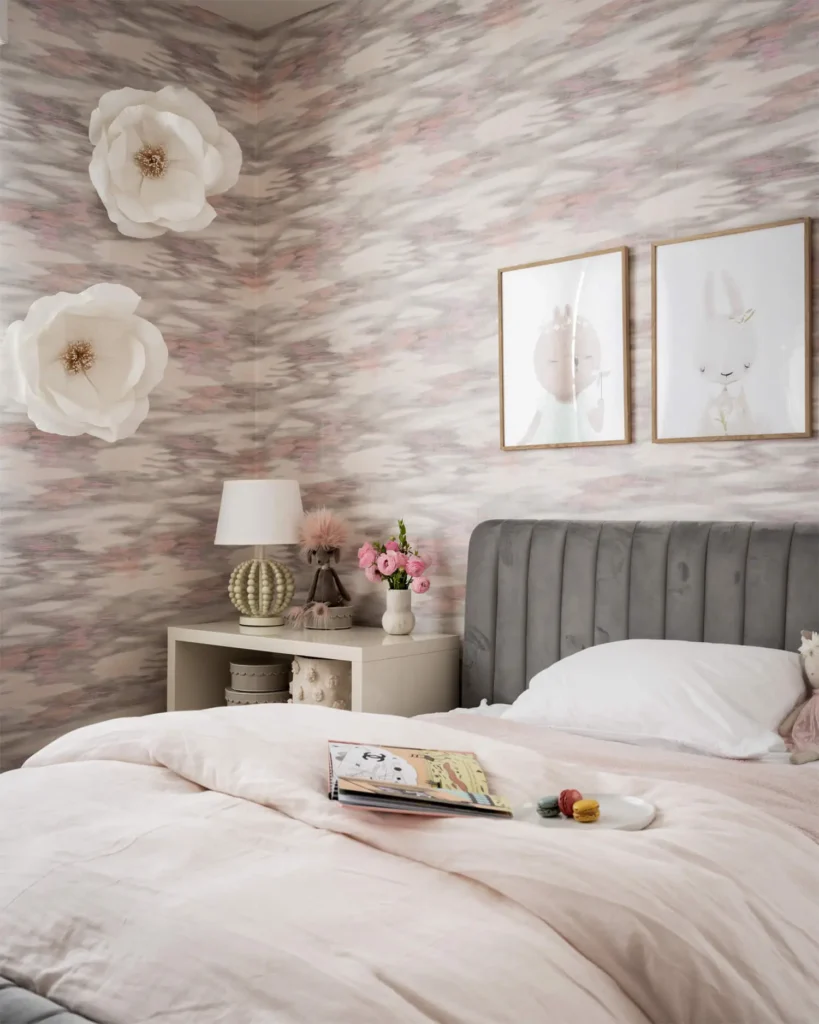 Soft pink bedroom with watercolor wallpaper, tufted gray headboard, oversized flower wall accents and blush bedding designed by Grace Blu Interior Design.