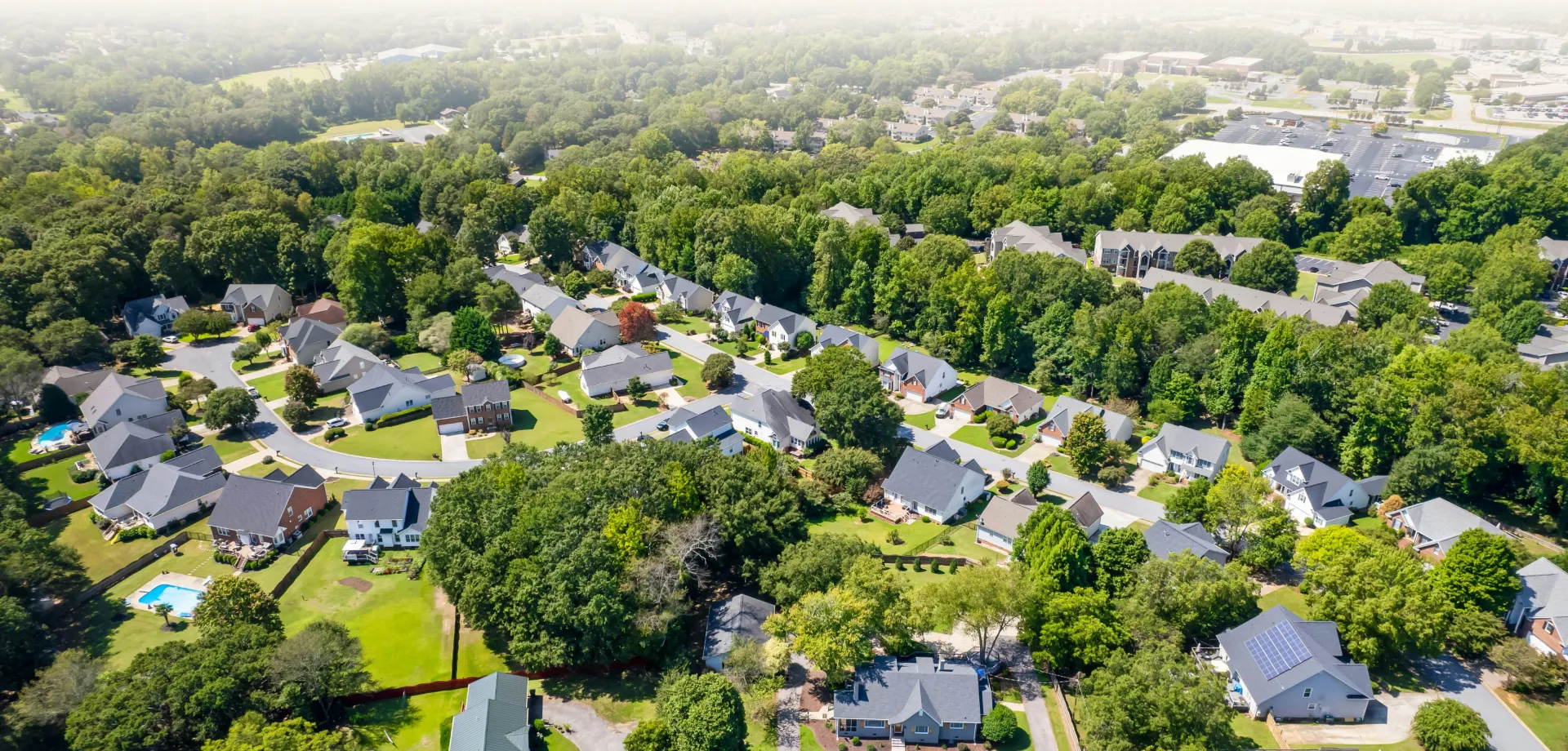 Aerial view of a nice neighborhood in Bluffton, South Carolina with large, green trees nestled within the rows of houses and in the background