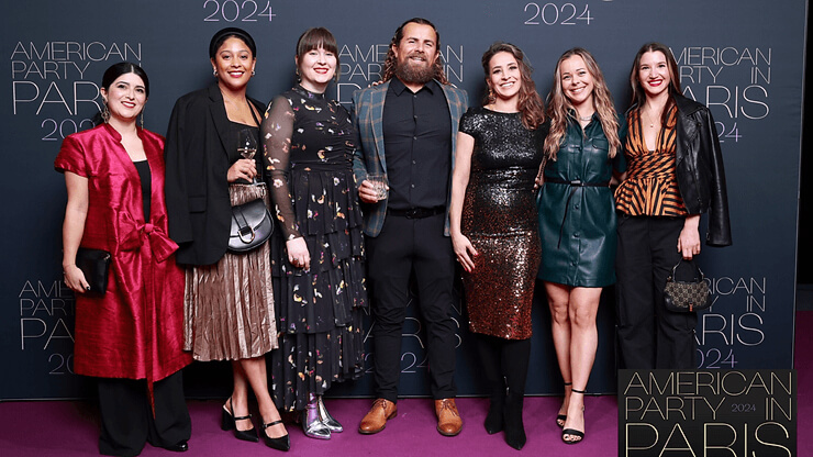 Group photo of Grace Blu team in stylish outfits at American Party in Paris 2024 step-and-repeat backdrop during design inspiration trip.