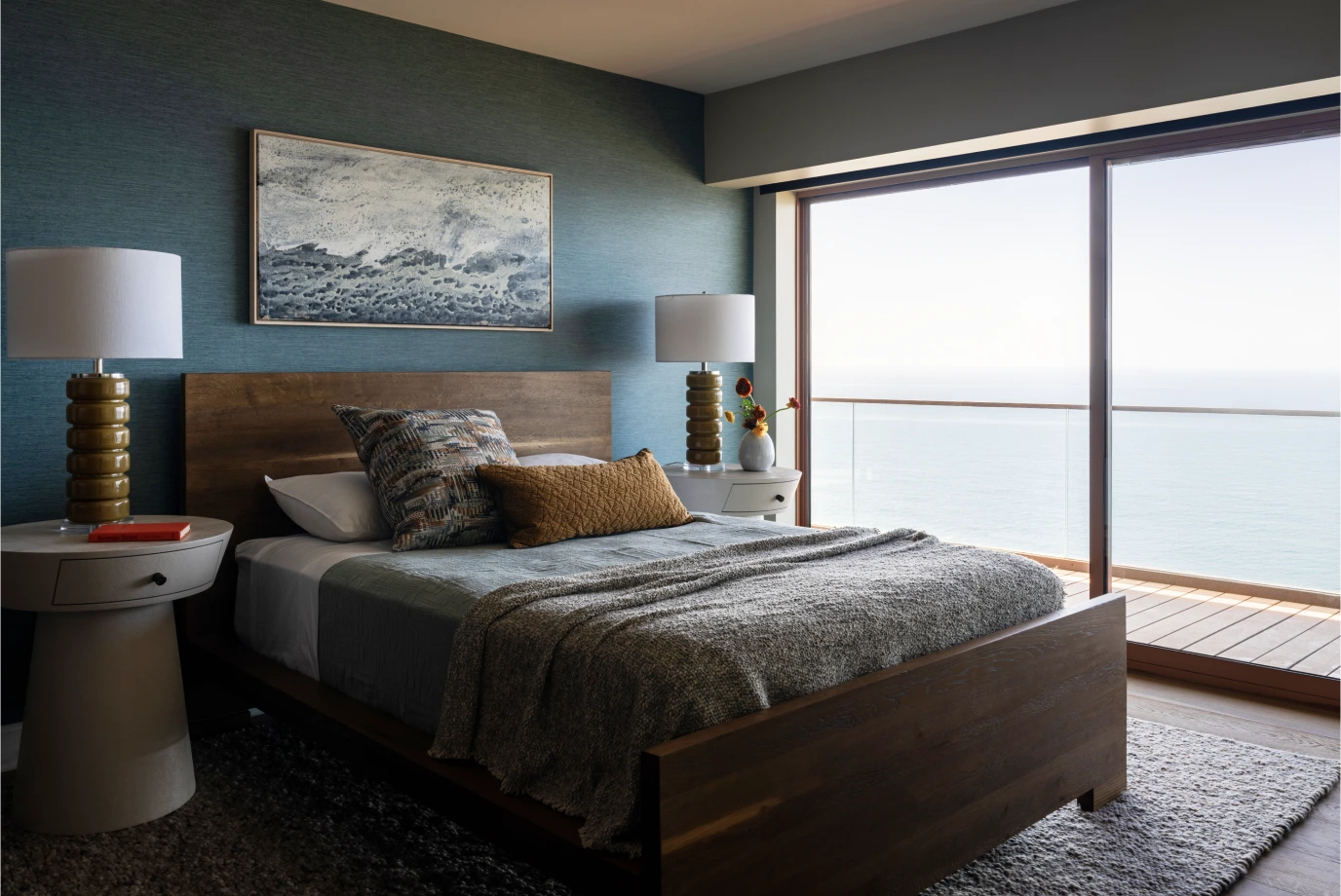 Guest bedroom from Grace Blu’s Va Va Views with wood platform bed, blue wallpaper, and ocean views.