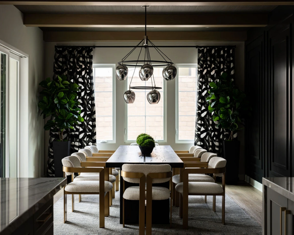 Trailmaster dining with wood table, statement chandelier, and tall greenery.