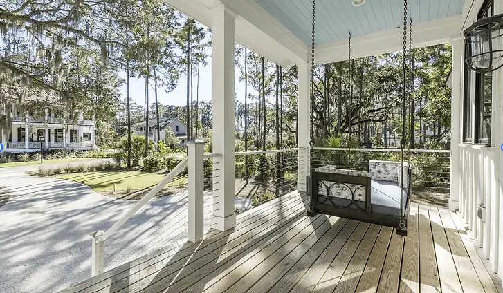 Southern porch with hanging swing bench, white columns and rope accents overlooking oak trees draped with Spanish moss, representing Grace Blu lifestyle inspiration.