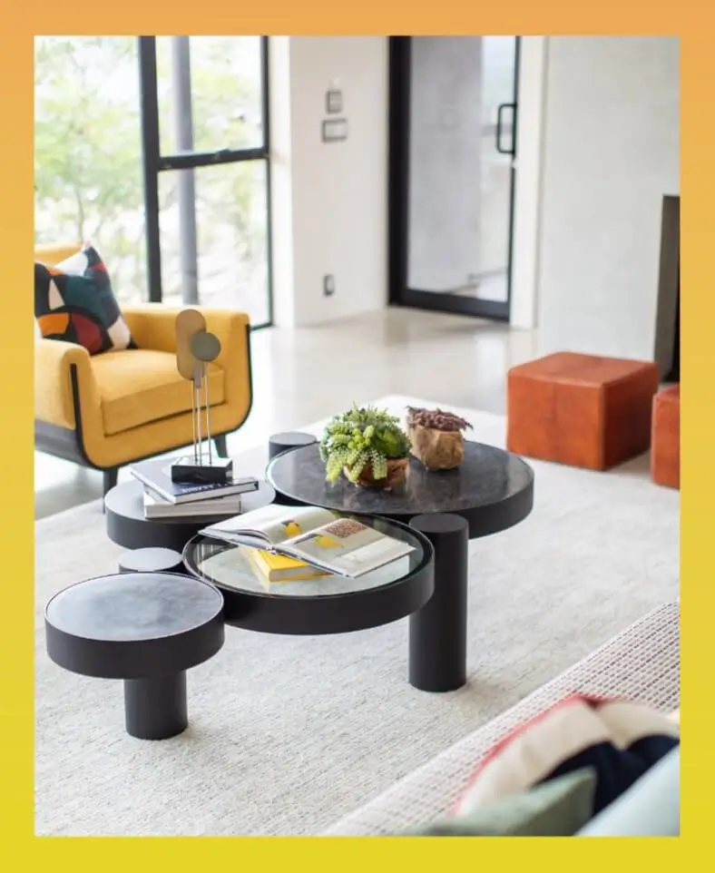 Living space from Grace Blu’s Trailmaster Interior Design Project with modern yellow armchairs, round coffee tables, and floor-to-ceiling windows.