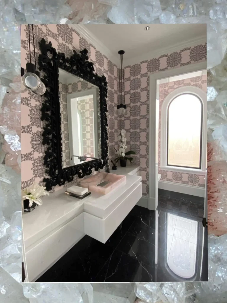 Elegant powder room designed by Grace Blu featuring patterned wall tile, dark wood trim and vanity, a marble countertop, and a framed portrait adding a touch of vintage charm.