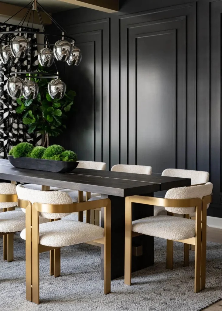 Contemporary dining room with black paneled walls, black table, cream chairs, chrome pendants and green moss centerpiece, designed by Grace Blu Interior Design.