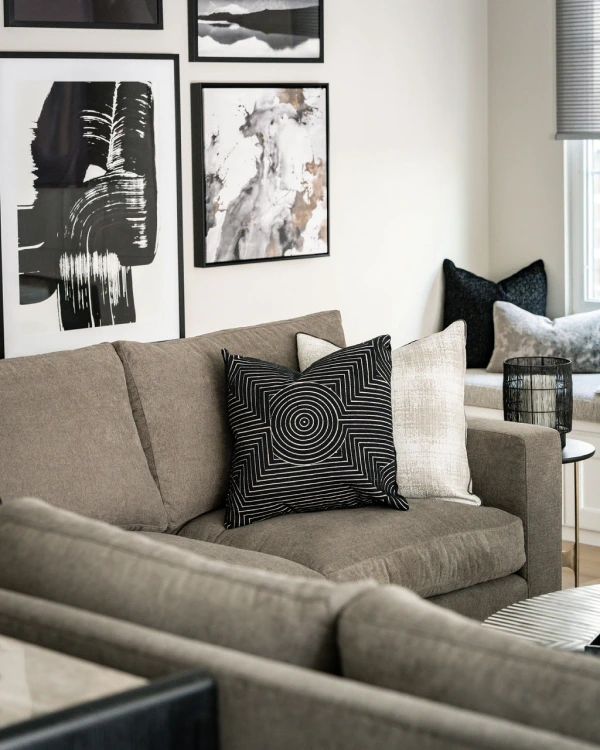 Neutral-toned living room from Grace Blu’s Trailmaster project with modern gray sofa, black and white artwork, and plush accent pillows.