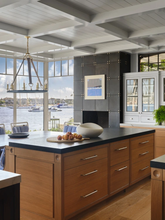 kitchen island with brown drawers and black table top with an ocean view with boats in view