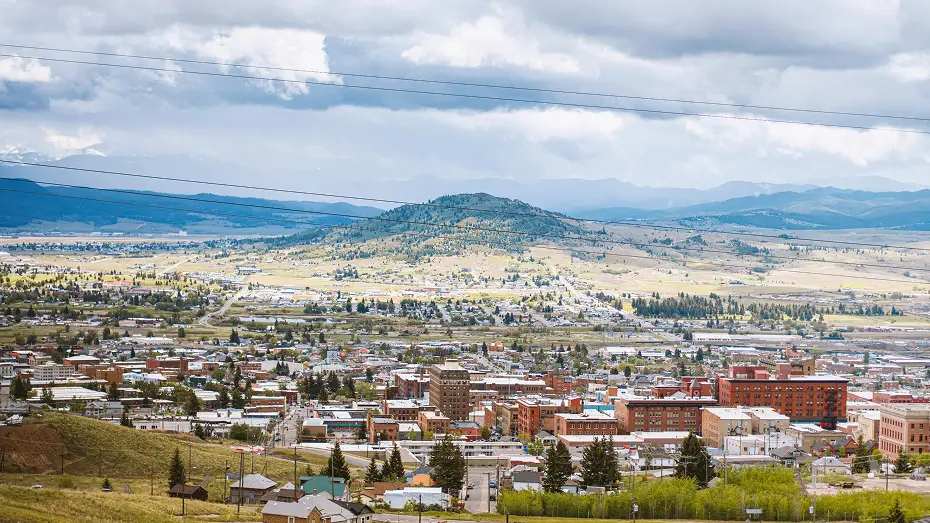 Aerial view of Big Sky, Montana showing a small town and rolling hills with mountains in the background, captured for Grace Blu Interior Design