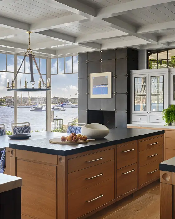 kitchen with wood island, marble counter, striped plates, sailing sculptures and waterfront views through windows