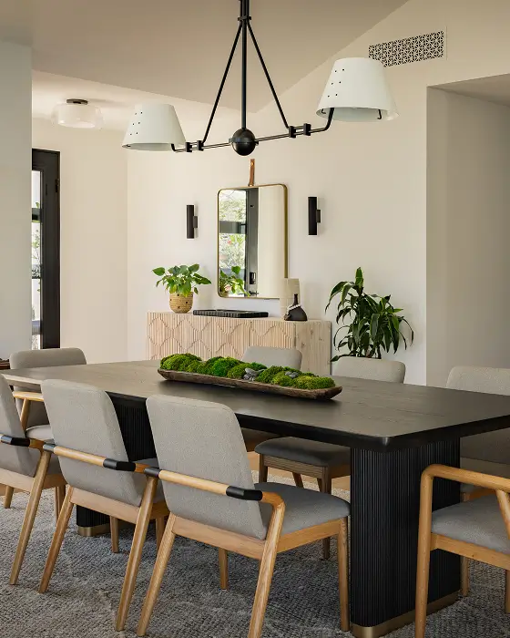 Dining space with high wood chairs and grey cushions, black pendant light overhead and wooden bar cabinets behind