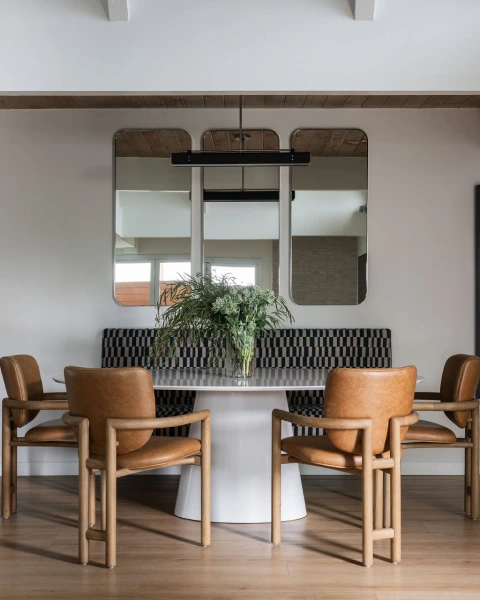 Bungalow Shores built-in bench with tall mirrors, white table, and four leather chairs.