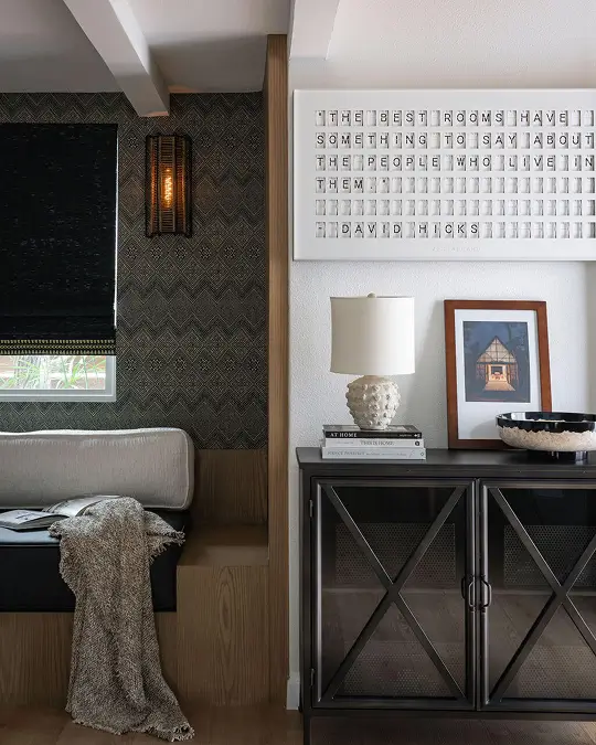 Entry vignette with black console table, framed art, and letter board beside a cozy bed nook from Grace Blu’s Bungalow Shores project.