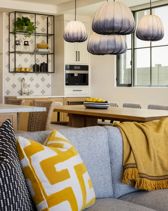 Living room from Grace Blu's The Happy Place Interior Design Project with a light gray couch, abstract gray lamps, with yellow accents from the pillow and blanket