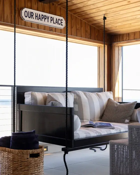 Dark gray patio couch swing from Grace Blu's The Happy Place Interior Design Project inside a room made of light brown wood panels