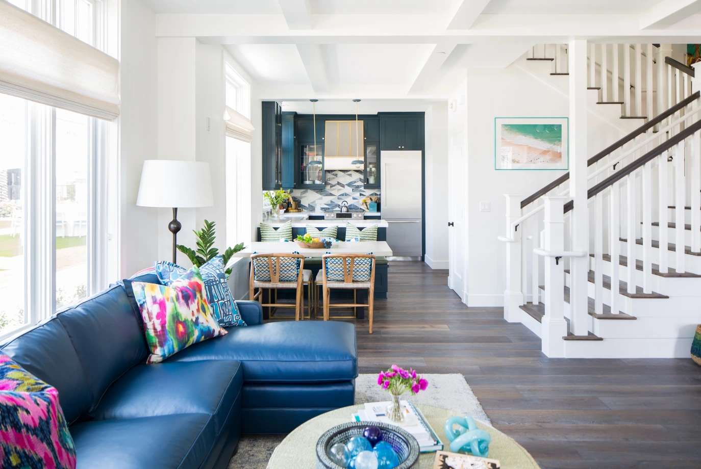 Lido House living space with navy sectional, colorful pillows, and open kitchen-dining view.