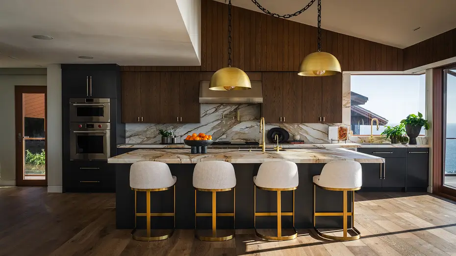 Kitchen with tall ceiling, wood paneling and marble counters, art above cabinets, striped runner and white chairs