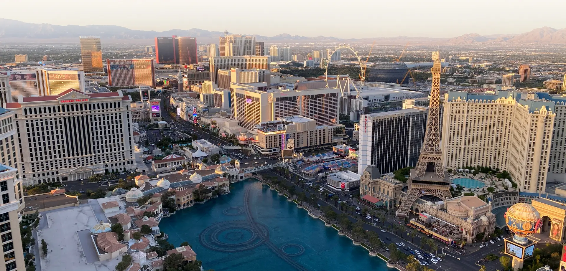 Aerial view of downtown Las Vegas at sunset, with warm sunlight casting golden highlights on the rooftops of high-rise buildings
