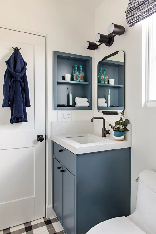 Bathroom from Grace Blu's Interior Design Project Park Ave with faded blue cabinets and organizational cubby featuring white marble countertops