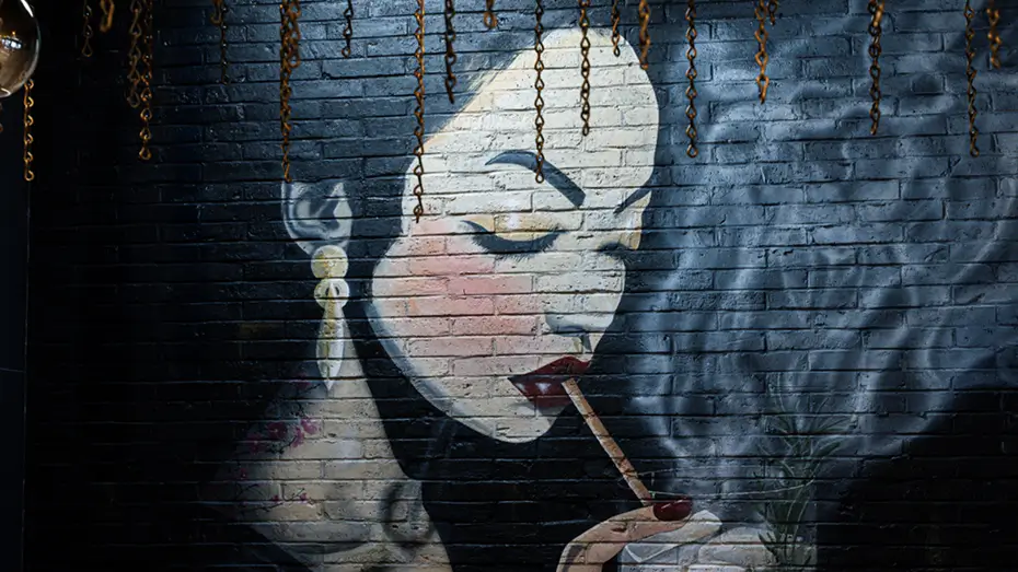 Mural at Yuzu Sushi of an elegant woman with bold makeup smoking beside a drink.