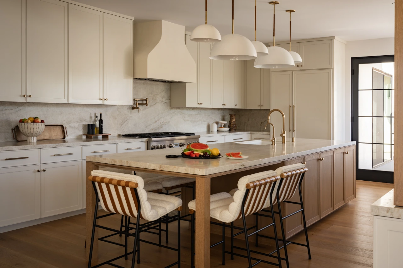 Kitchen area from Grace Blu’s Interior Design Project Rattan Galore with pendant lights, white countertops, and cane-back barstools.