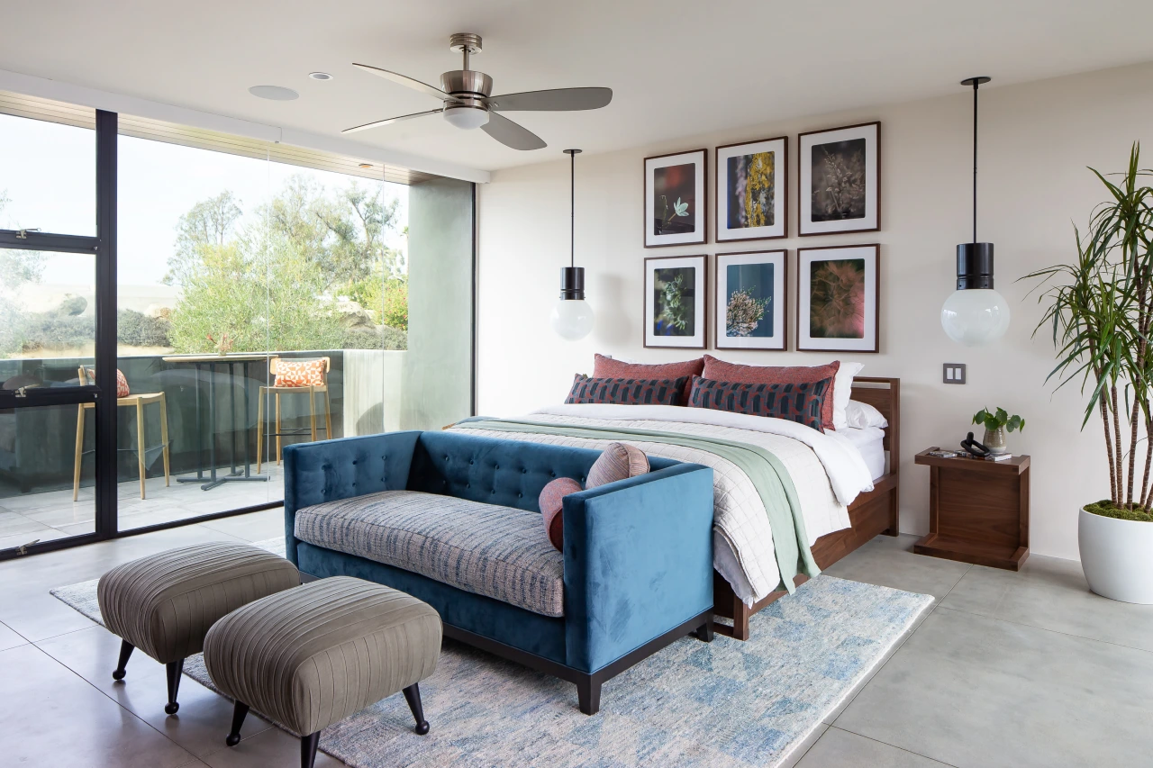 Sommet du Monde bedroom with queen bed, dark blue sofa, and six colorful frames above the headboard.