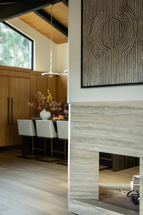Travertine fireplace with warm travertine stone and view into wood kitchen.
