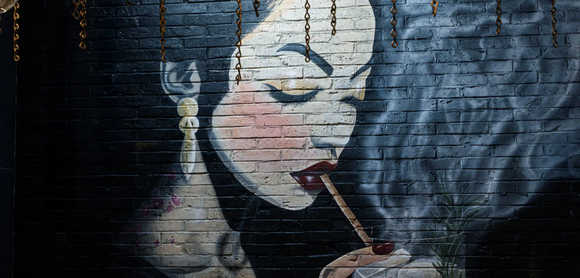 painting of a woman smoking a cigarette on a brick wall in a restaurant
