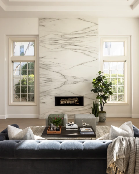Charlotte living room with marble fireplace, navy sofa, black table, and windows.