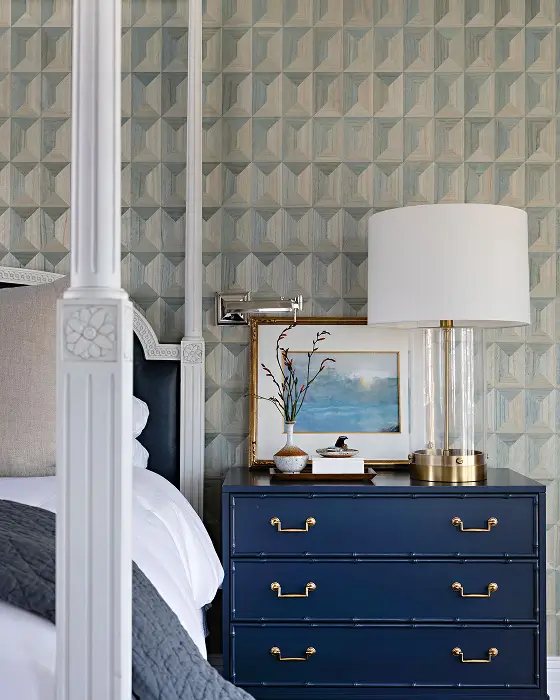 Bedroom with dark blue and white striped wallpaper and bed with white posts, accented with gold details