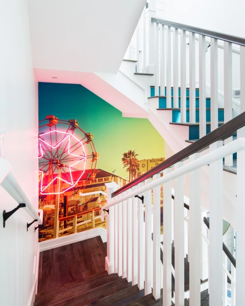 Lido House stair mural with lighting and colorful beach carnival scene with ferris wheel.