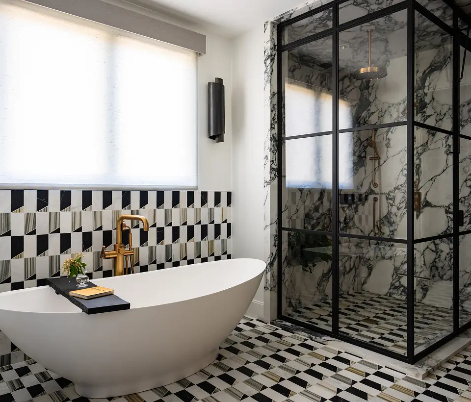 Luxurious bathroom with freestanding tub, geometric tile, gold fixtures, and glass-enclosed marble shower.