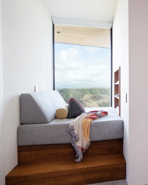 Lounge area in Grace Blu's Interior Design Project Sommet du Monde with a mini couch placed in a nook against a large window with a view