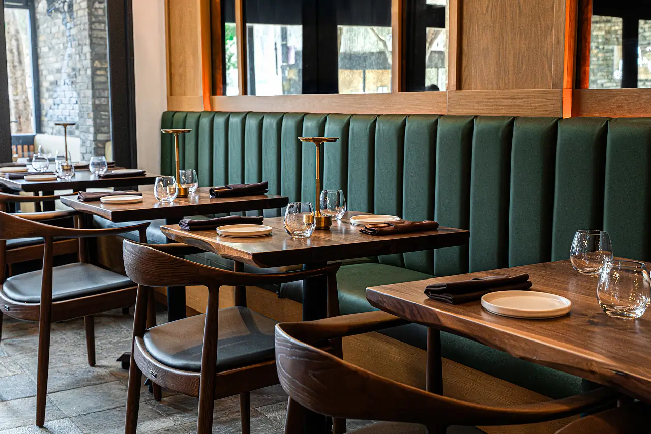 Elegant Yuzu Sushi dining area with green booth seating, wood tables, and modern place settings.