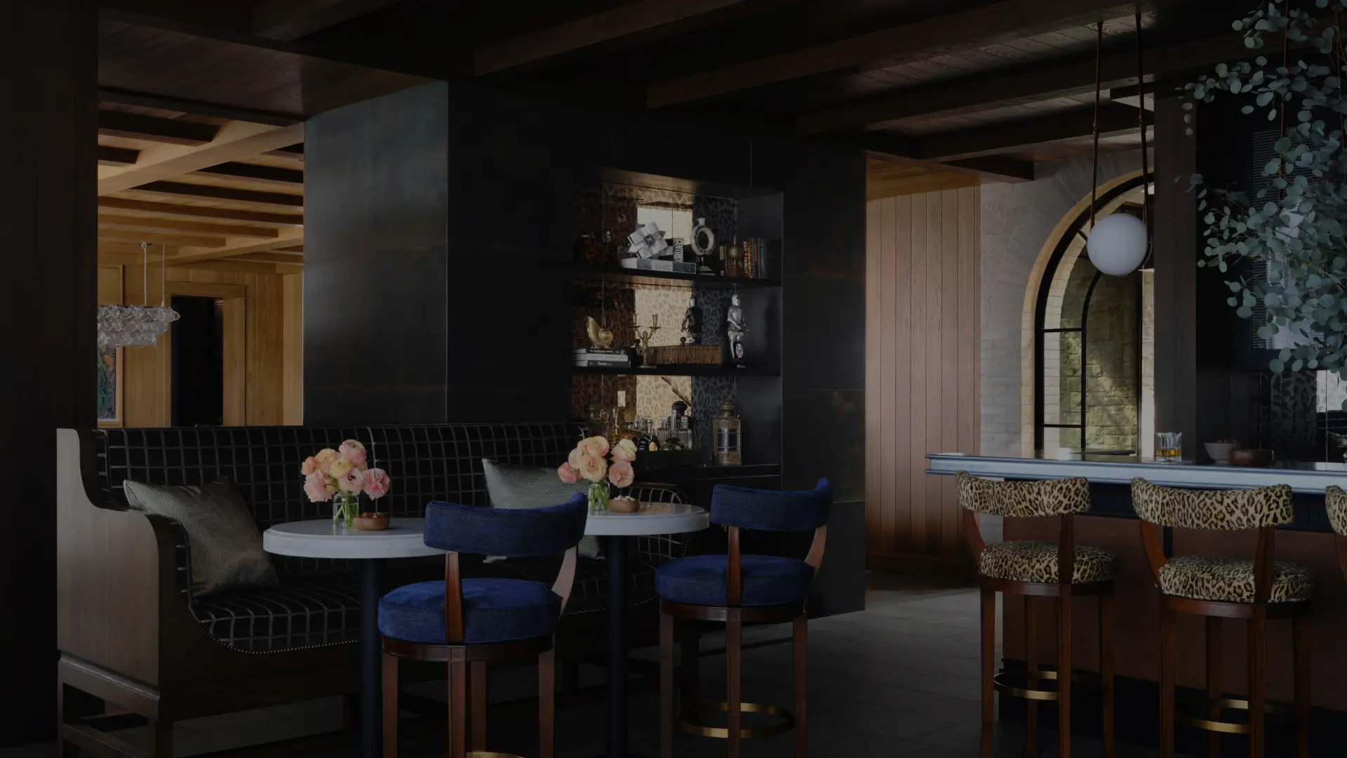 Moody luxury lounge with velvet chairs, leopard barstools, dark wood paneling, and custom built-in bar shelving.