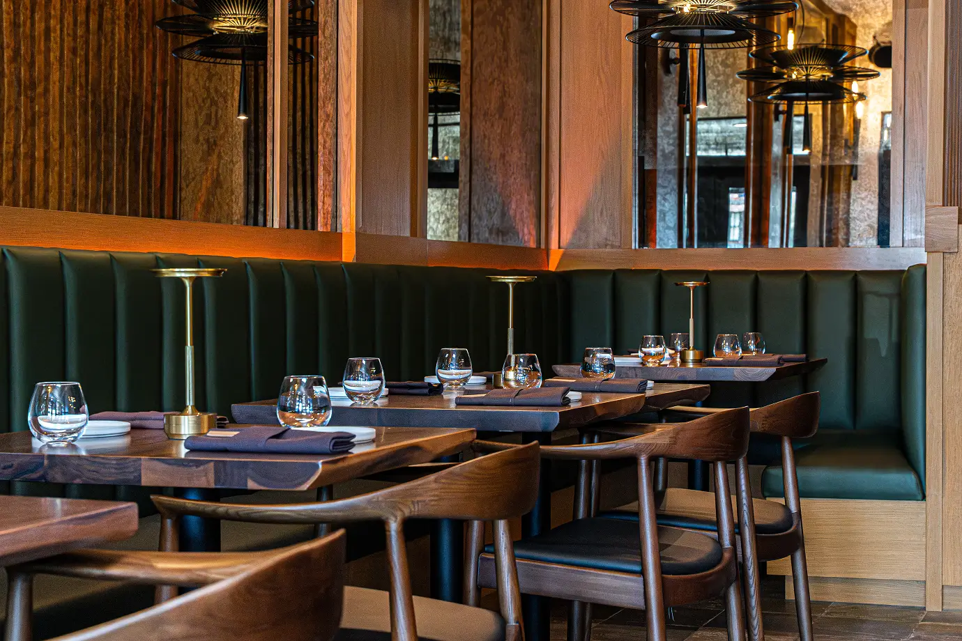 Elegant Yuzu Sushi dining area with green booth seating, wood tables, and modern place settings.