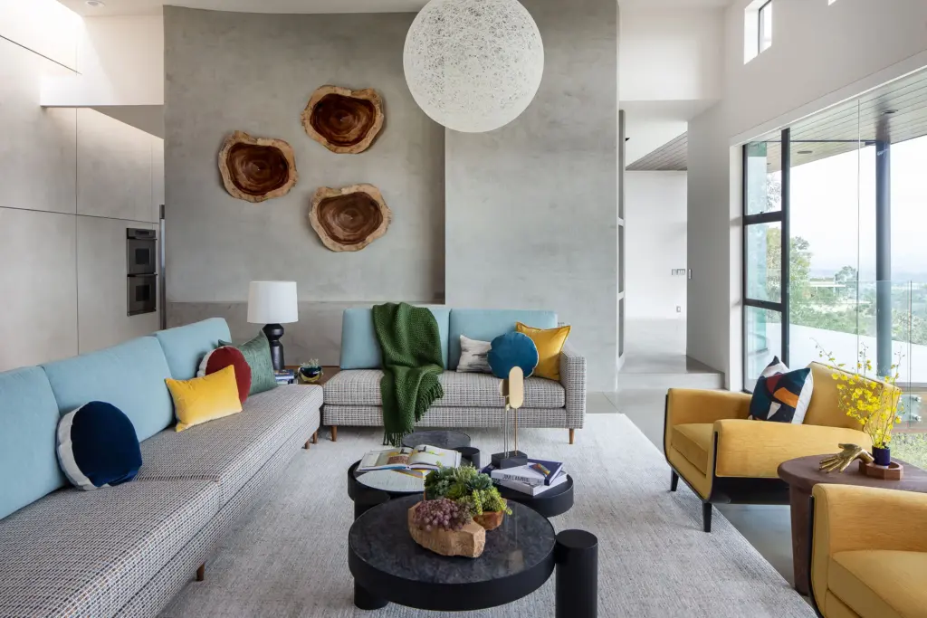Living room with teal sofas, yellow chairs and wood slice art on a plaster wall