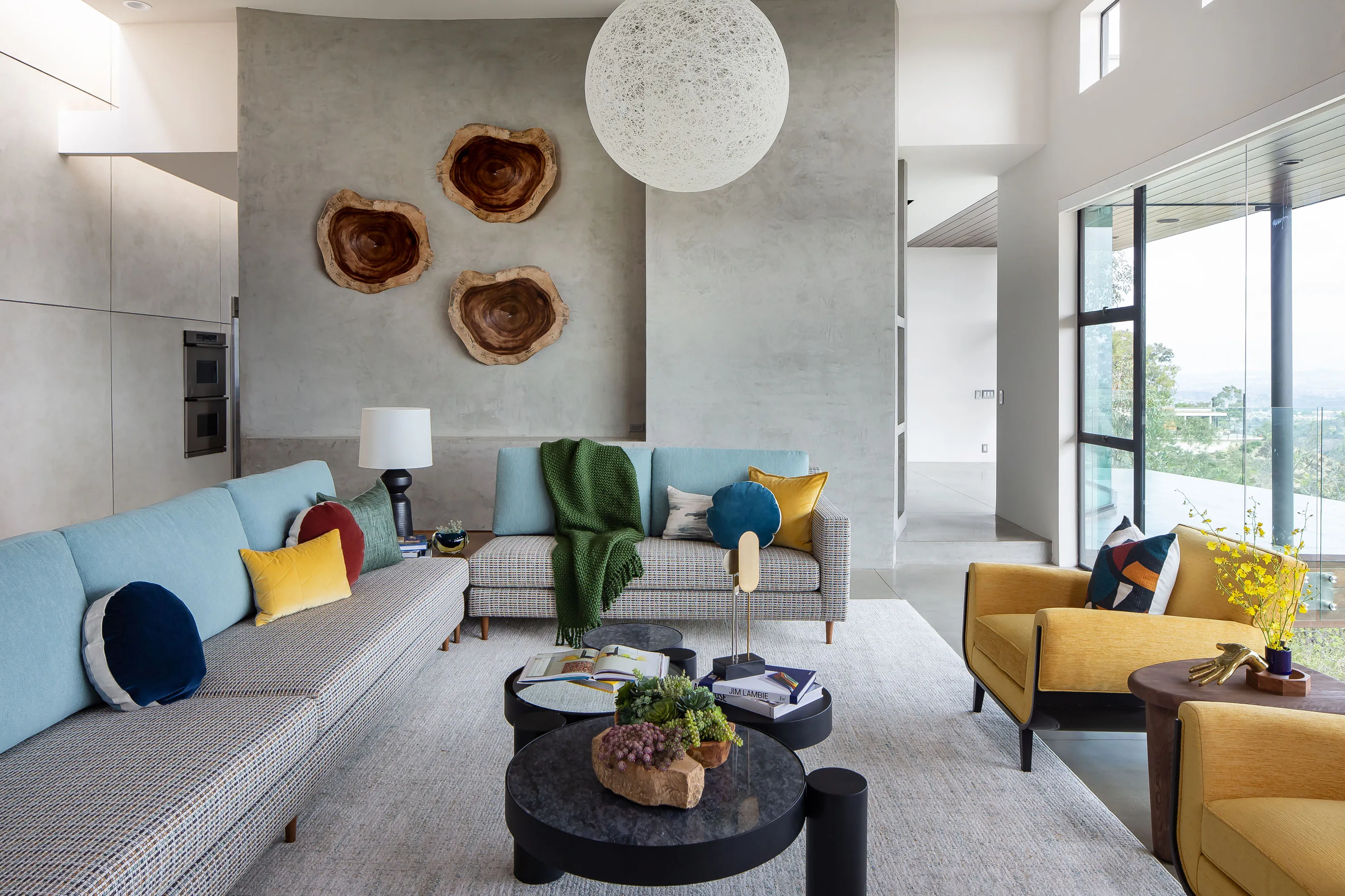Living room with teal sofas, yellow chairs and wood slice art on a plaster wall