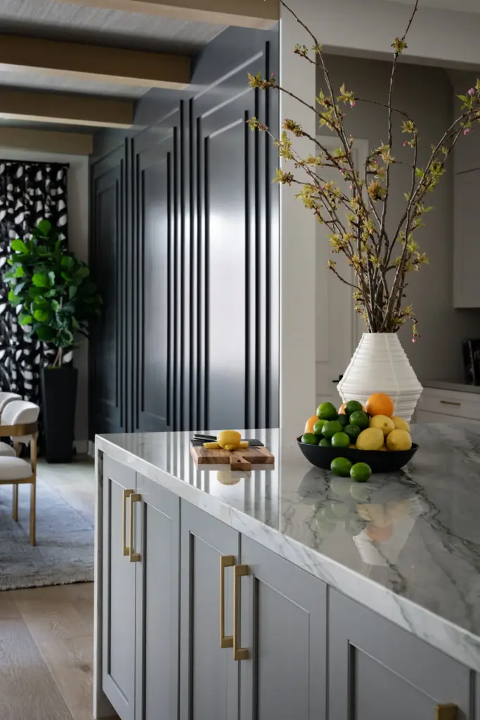 Gray kitchen island with marble countertop, brass hardware and a forsythia branch arrangement