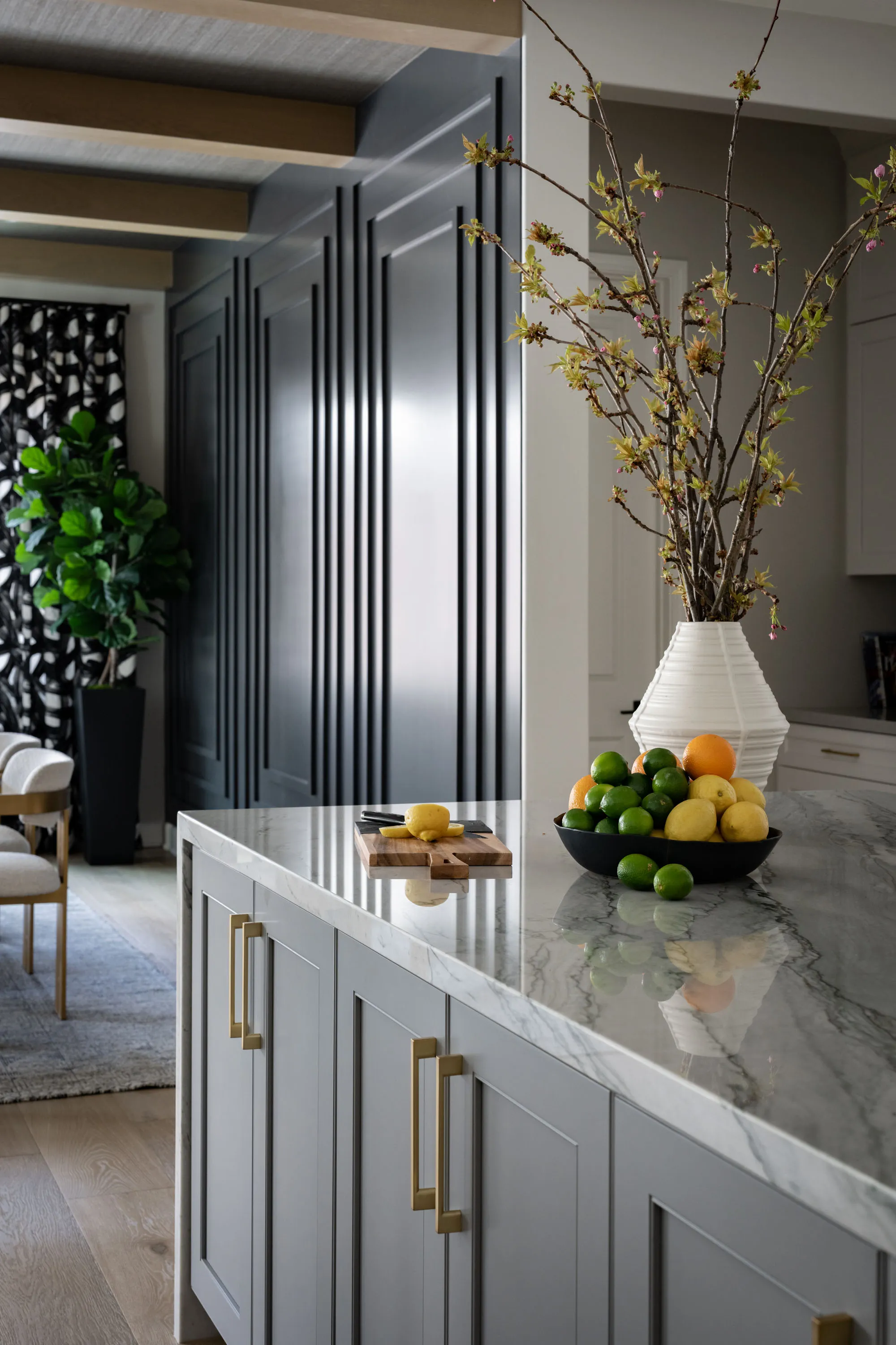 Gray kitchen island with marble countertop, brass hardware and a forsythia branch arrangement