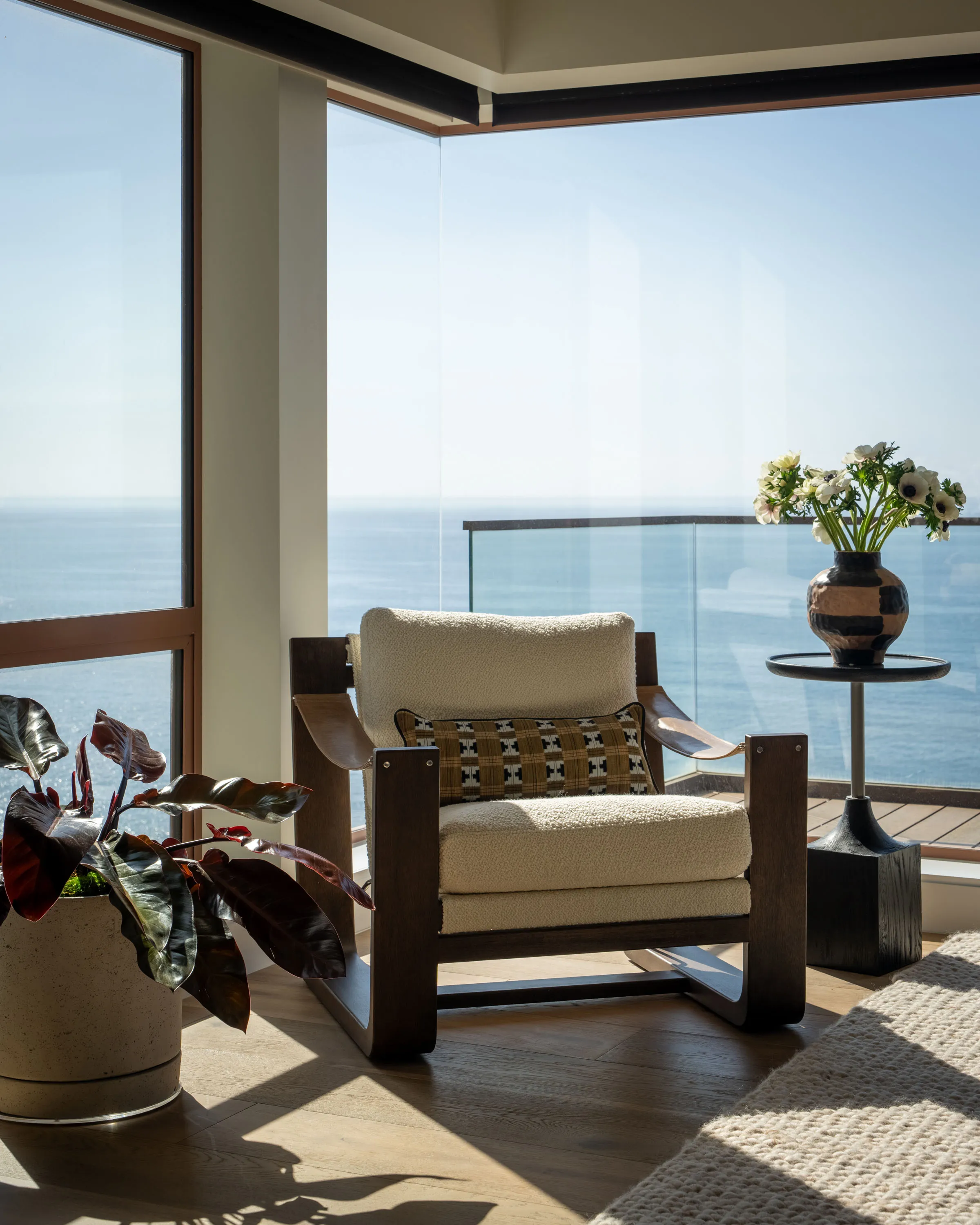 Boucle lounge chair in a corner window overlooking the ocean