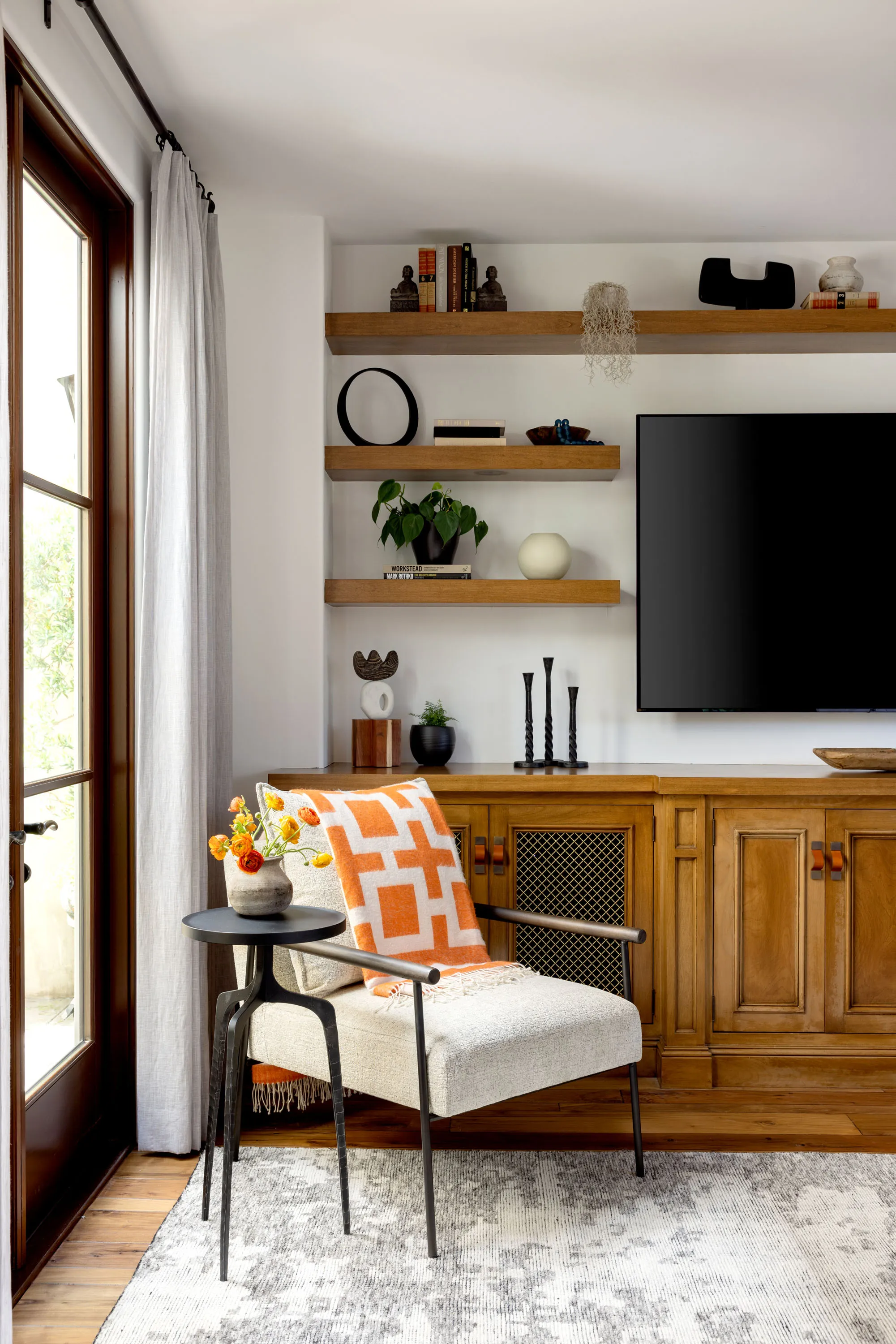 Family room with a wood built-in media cabinet, floating shelves and an accent chair